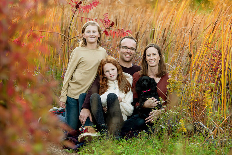 mom and dad sitting on the ground with their son daughter and dog for their fall family photos in Burlington, Ontario