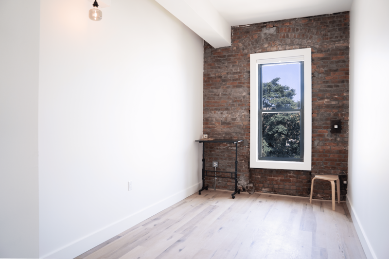 Large, bright therapy office in Brooklyn, NY featuring an exposed brick wall and plenty of natural light coming in through the windows.