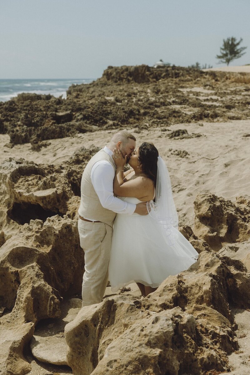 bride and groom share a kiss on the beach