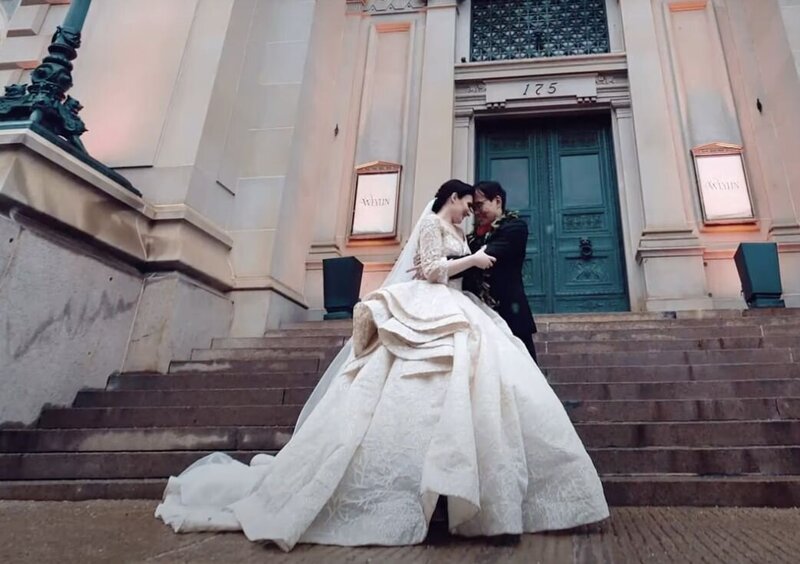 A newlywed couple standing forehead to forehead on a staircase 