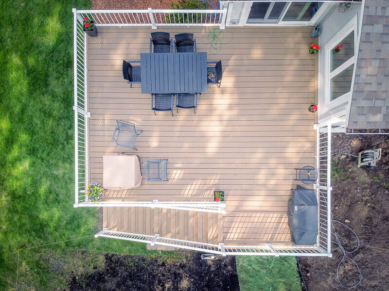 Aerial top view of a TimberTech Composite deck with white railing and outdoor furniture. 