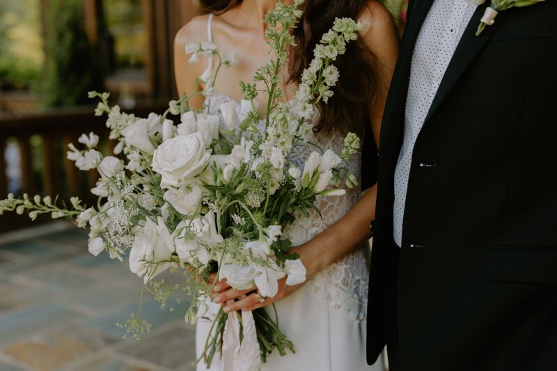 A bride holding a white and green bouquet next to the groom at their Nashville wedding