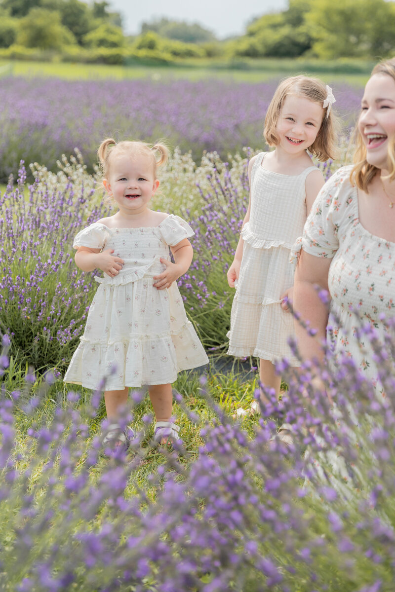mother and two daughters laugh together in a lavender field