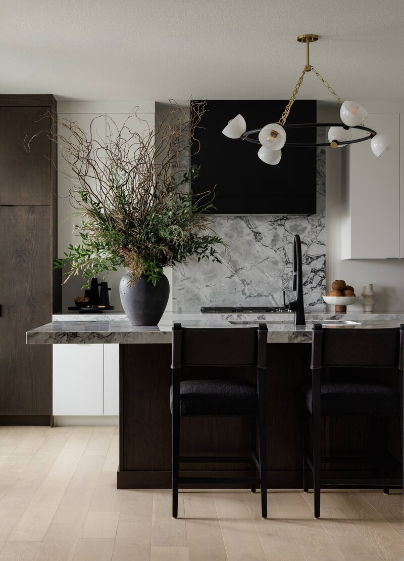 A contemporary kitchen with grey quartz countertops and backsplash with round ceiling fixture.