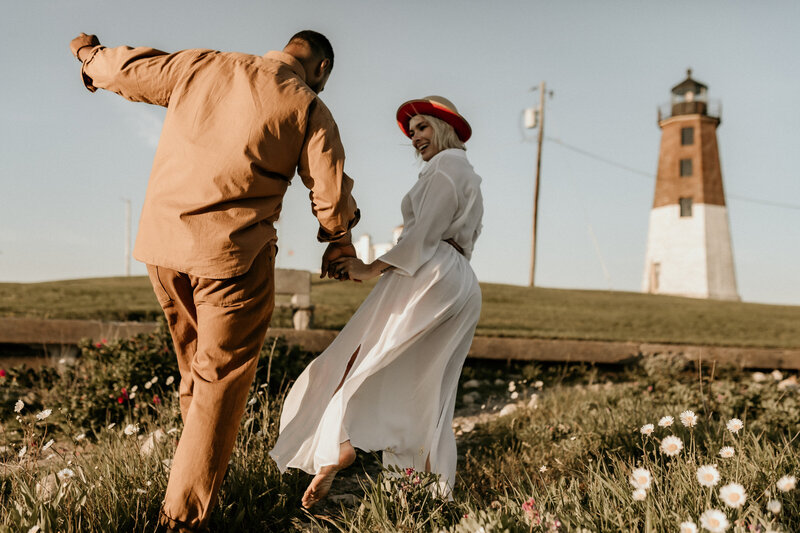 couple walk in front of lighthouse