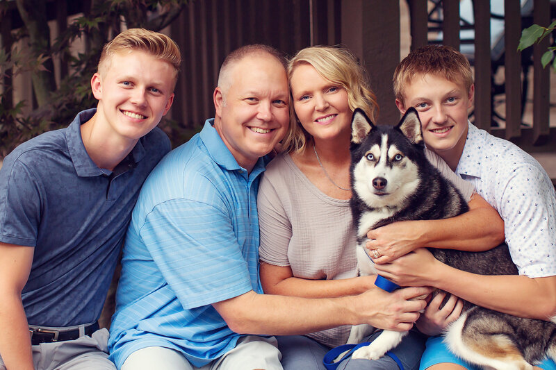 Nice portrait of a family of four, two teenage boys, and their husky dog, in their back yard.