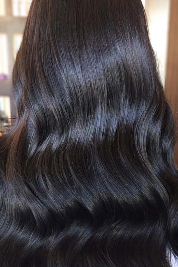 Shiny, sleek black hair styled in soft waves, highlighting professional hair treatments at Blake & Kwan Caringbah.