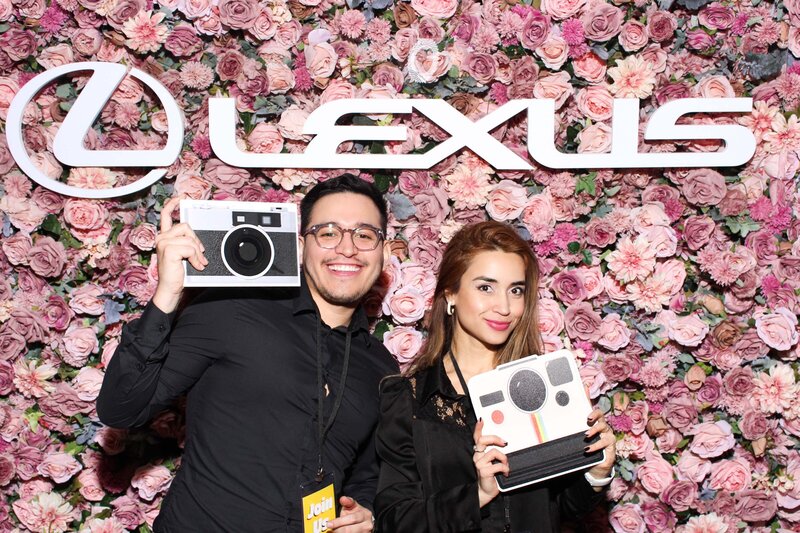friends holding camera props, in front of a majestic flower wall with a LEXUS sign on top.