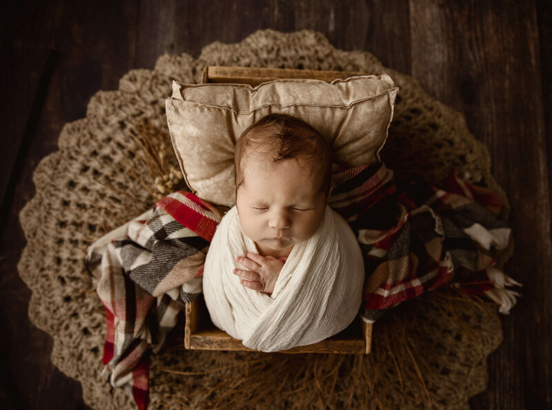 Newborn photo of a baby boy wrapped on a plaid blanket