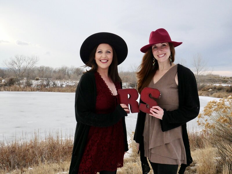 Women in golden light, wearing dark rimmed glasses and striped shirt, smiling down at her hands as she rolls out clay