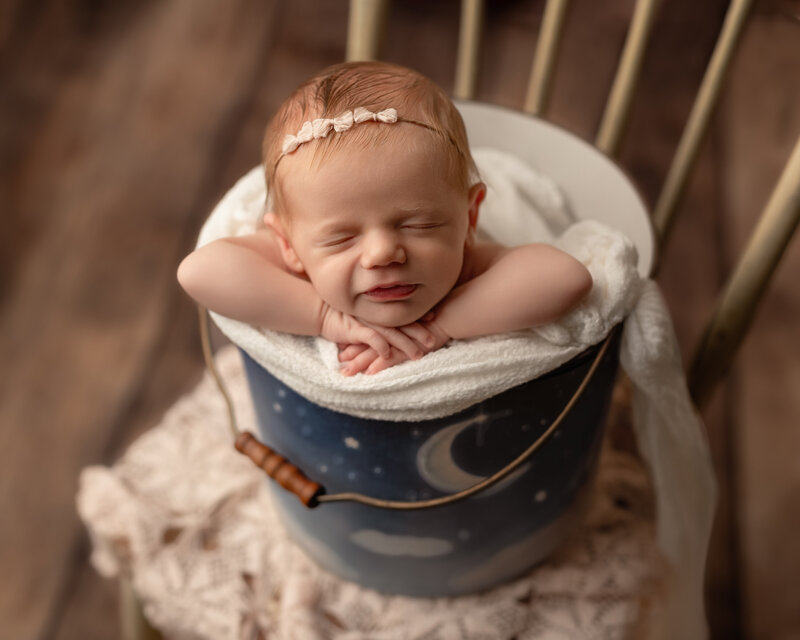 A celestial bucket photo featuring a newborn girl in dreamy moonlight tones and soft handcrafted details.