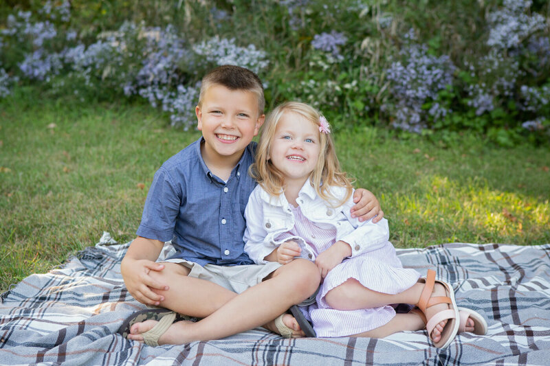 Brother and sister toddlers sitting on a blanket