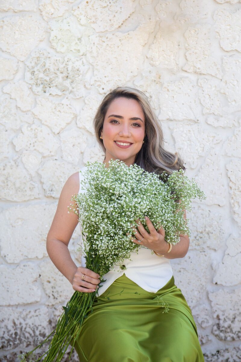 Merlyn Asencio holding a bouquet of baby’s breath with an encouraging smile, symbolizing support, care, and hope in her trauma therapy practice in Miami, Florida