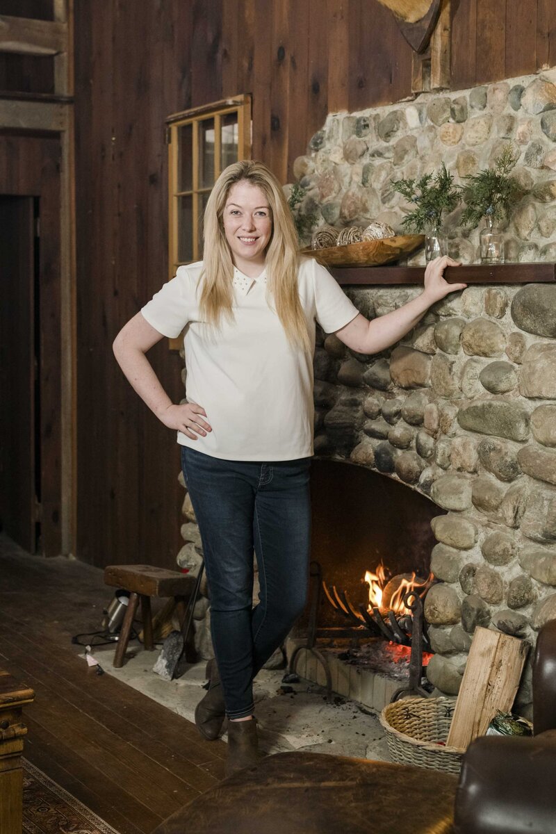 Amanda standing by the fireplace in the cabin