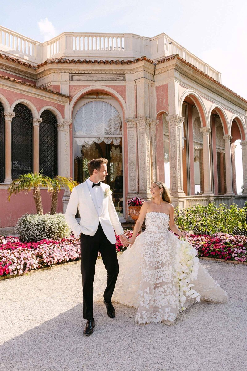 Bride and groom have a stroll holding hands with VIlla Ephrussi as a backdrop.
