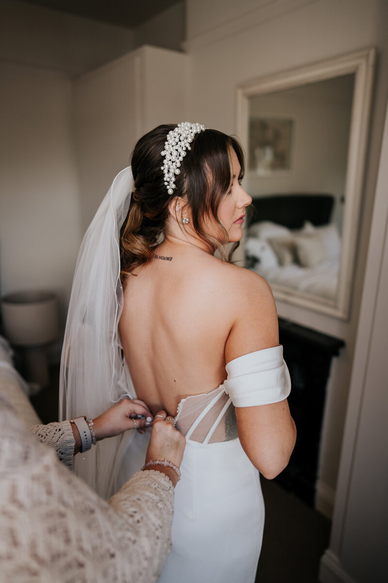 live action image of the wedding content creator helping the bride get into her dress