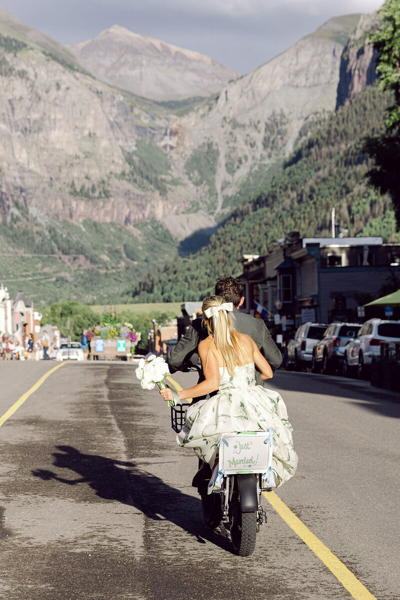 Bride and groom riding motorcycle into the distance