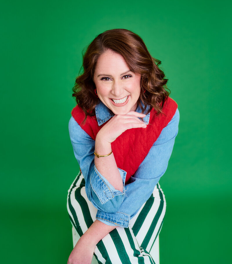 Jaime Bartol leaning forward smiling at camera with a green background