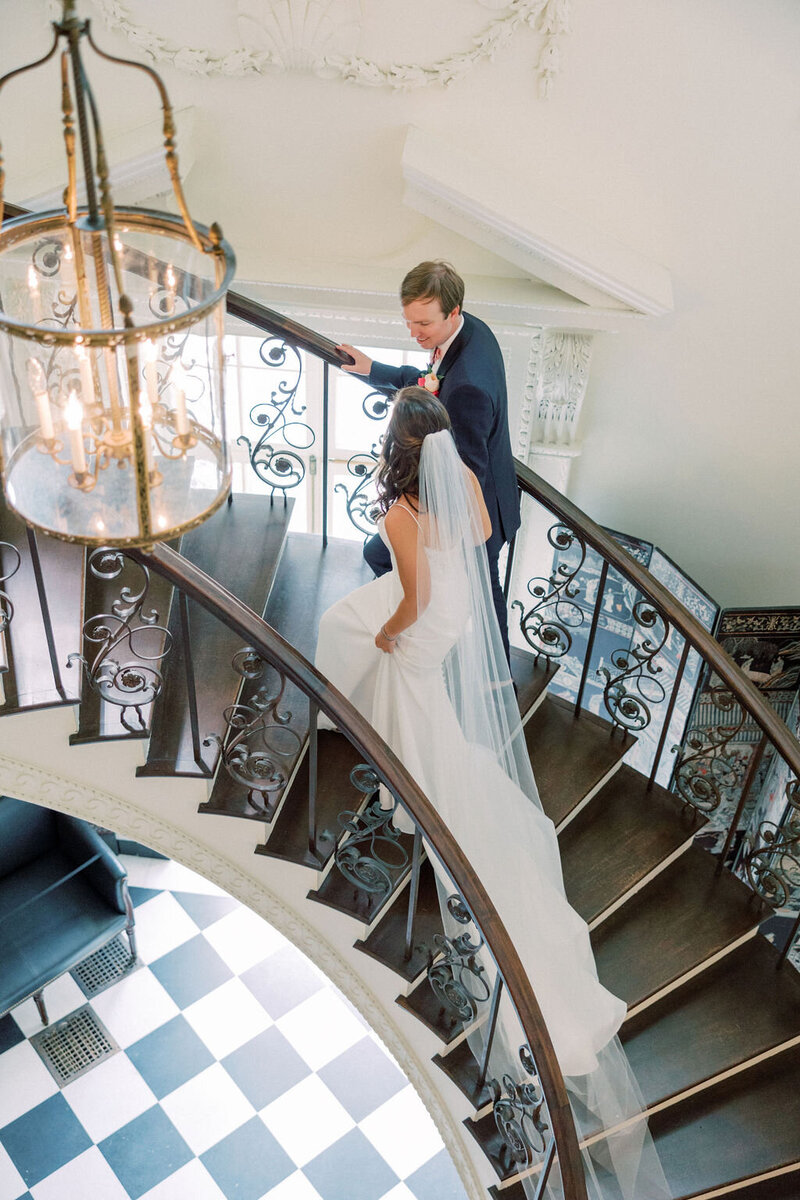 Bride and groom walk up curved staircase at the Atlanta History Center with black checkered floors