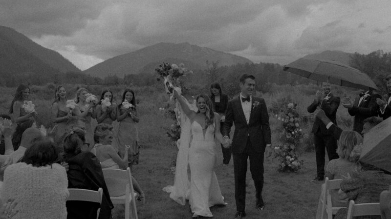 couple walking back down aisle after ceremony in front of mountain range