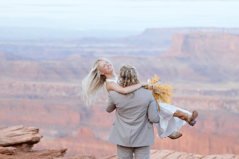 Groom spinning the bride with smiles on their faces during their elopement in desert Moab 