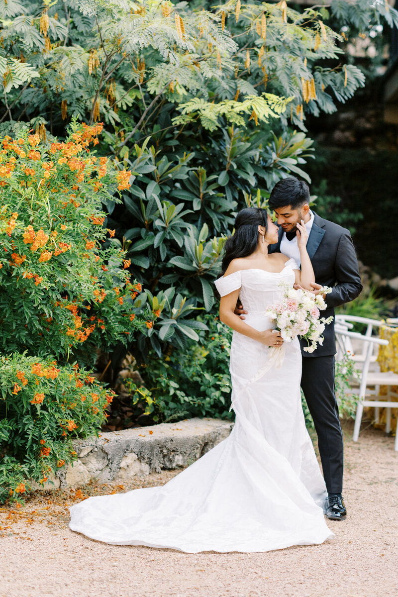 bride and groom stop mid-way down the flower-lined aisle to dip and kiss while guests smile and clap.