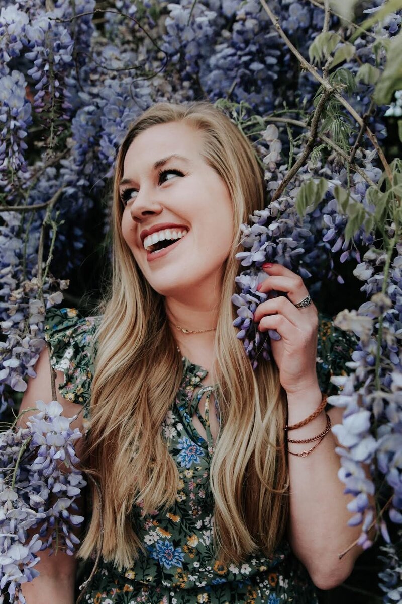 woman smiling while surrounded by wisteria