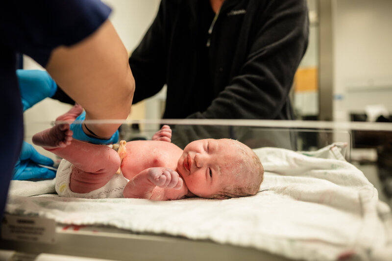 Newborn baby lying on hospital blanket with gentle lighting — Fresh 48 photography in Fort Worth by Poppy + Blue Photography