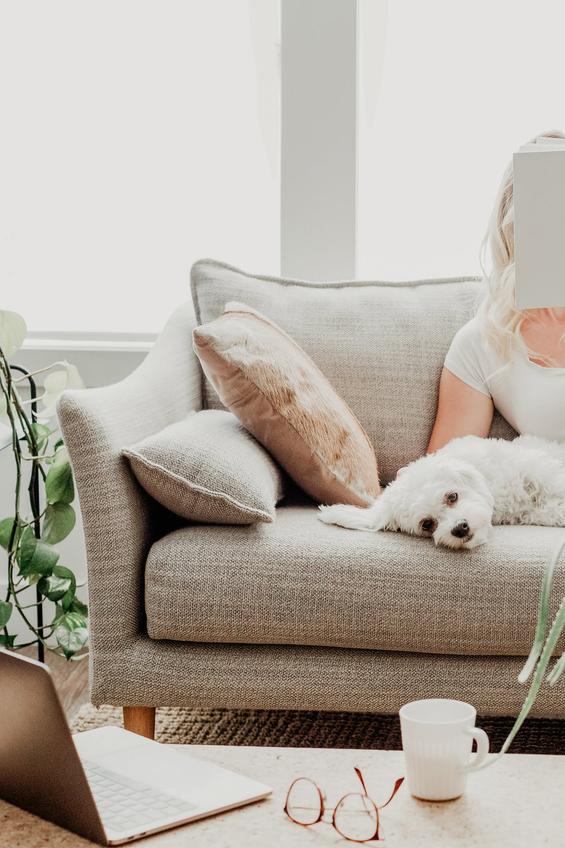 A woman on a couch with her dog