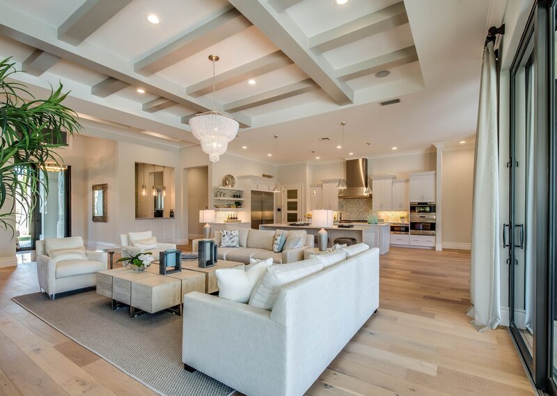 Staged living room with beige couches and vaulted ceilings and light wood flooring