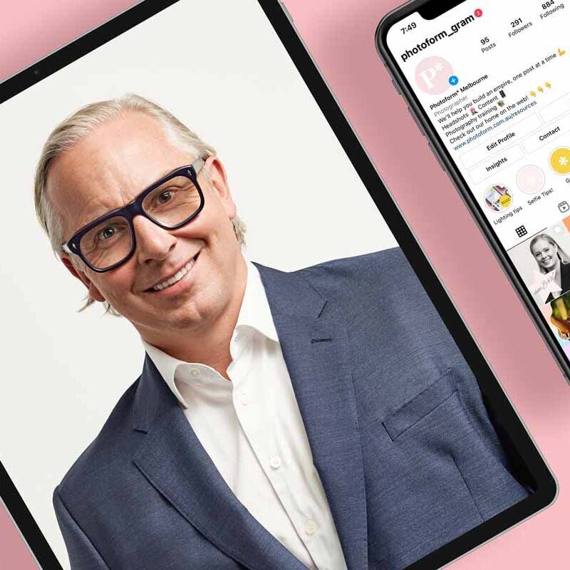 Smiling corporate woman with glasses against pink backdrop.