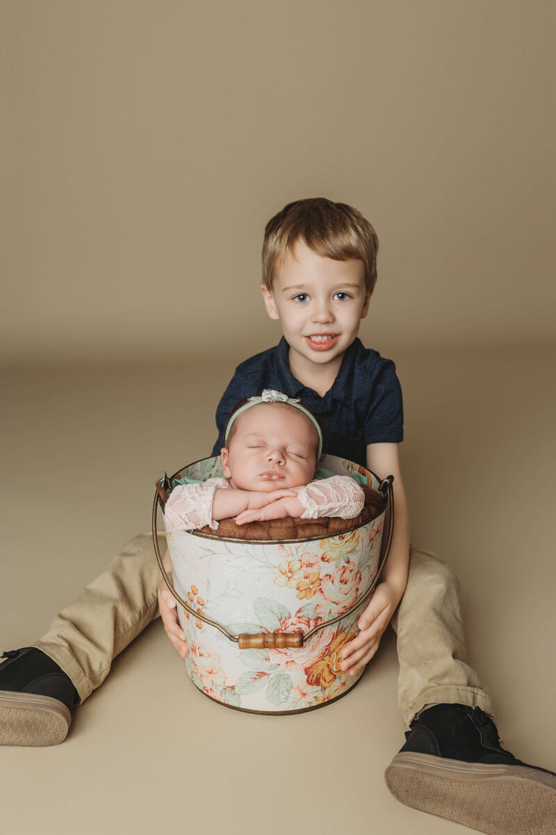 mom in a floral dress and dad in a green henley holding their newborn boy with their eyes closed