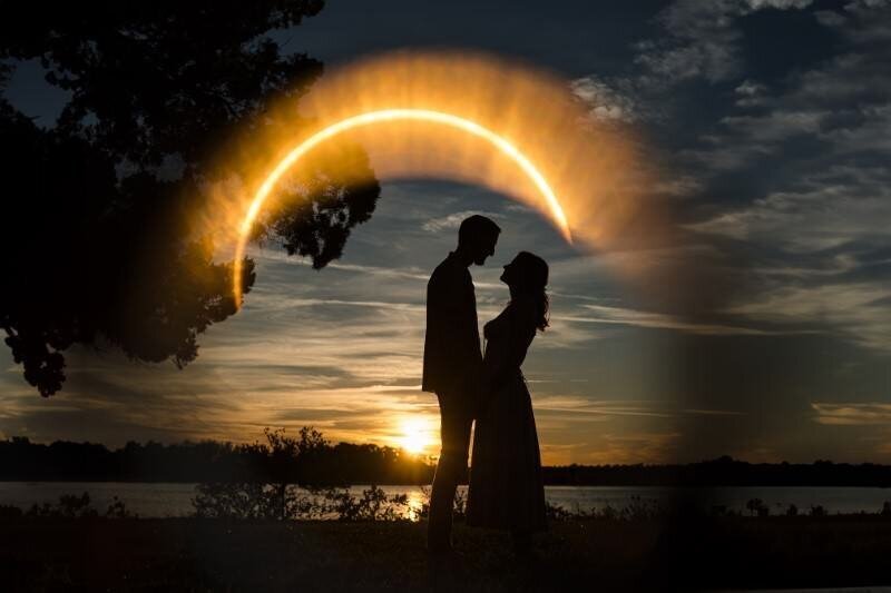 girl stands facing boy silhouetted by the sunet with the sun shining above them