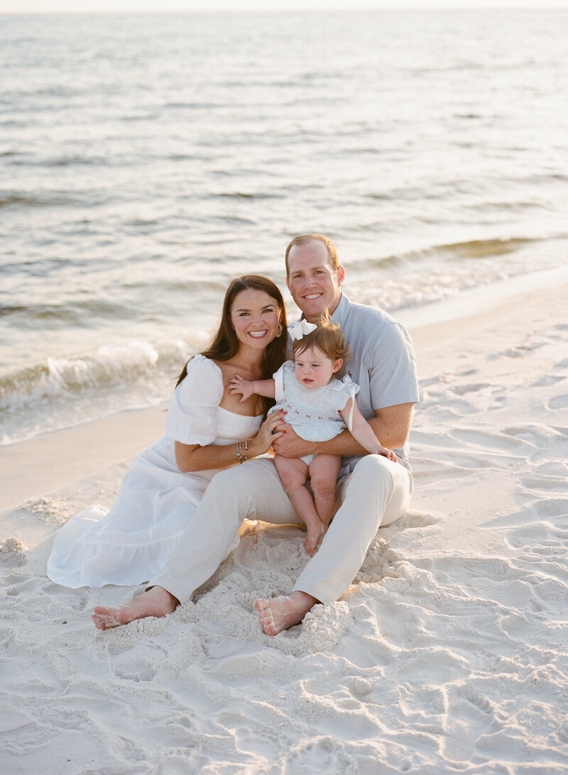 family sitting on the beach together 