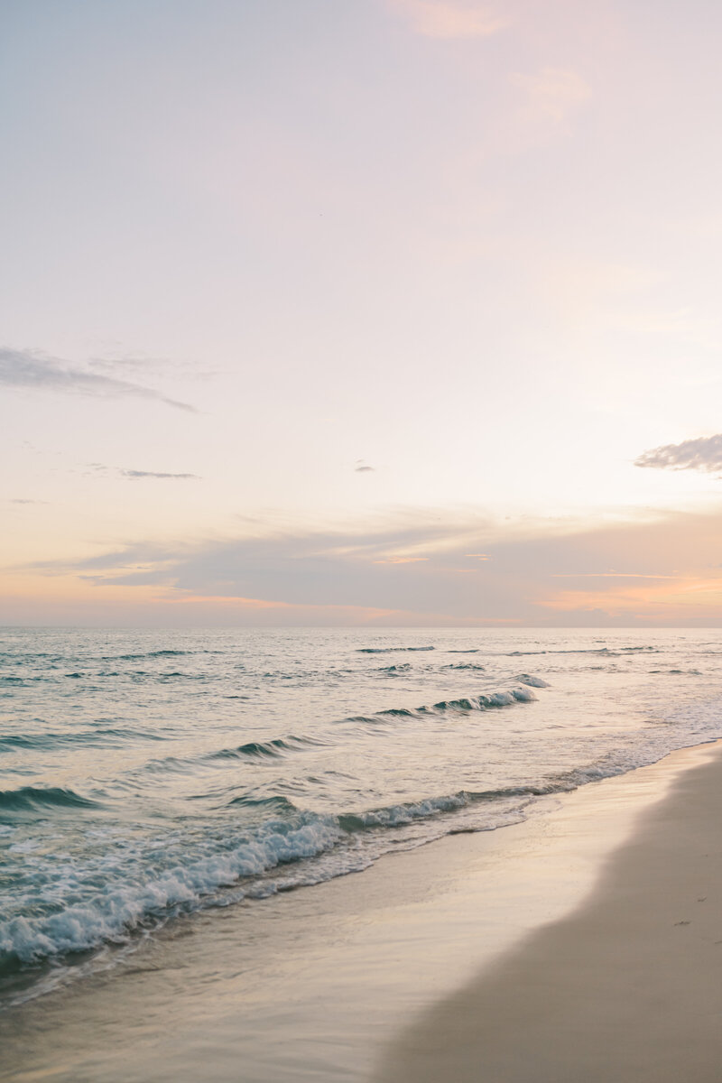 Image of a sunset on the beach with waves rolling on the sand