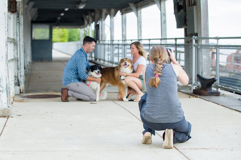 Jen Stitt capturing a heartwarming moment with an engaged couple and their dogs during an engagement session in Philadelphia, highlighting the couple’s bond and their love for their furry family members against the vibrant city backdrop.