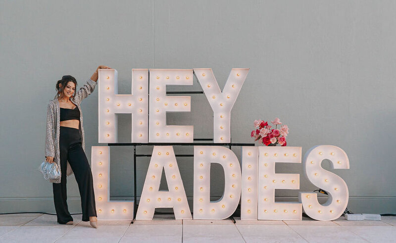 Cassandra posing with "Hey Ladies" sign