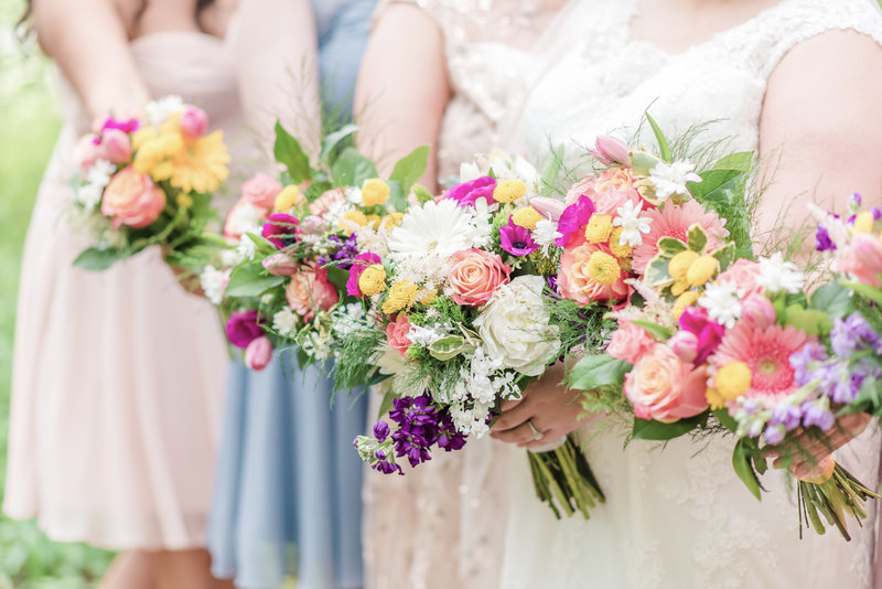 Detail shot of multi-colored bridesmaids dresses and bouquets