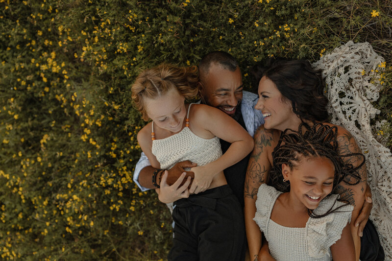 Family laying in a wildflower field giggling with each other.