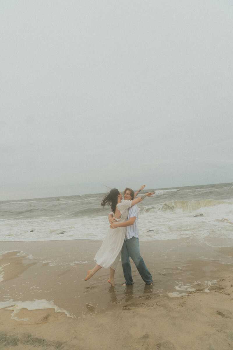 couple celebrates their engagement on the beach with a documentary photographer