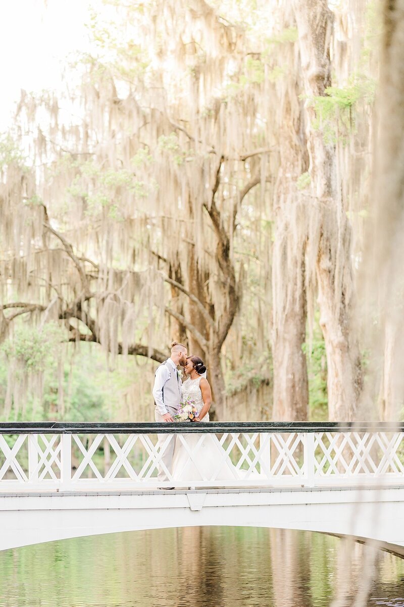 Bride and groom standing on bridge on their wedding day at magnolia gardens  in charleston south carolina