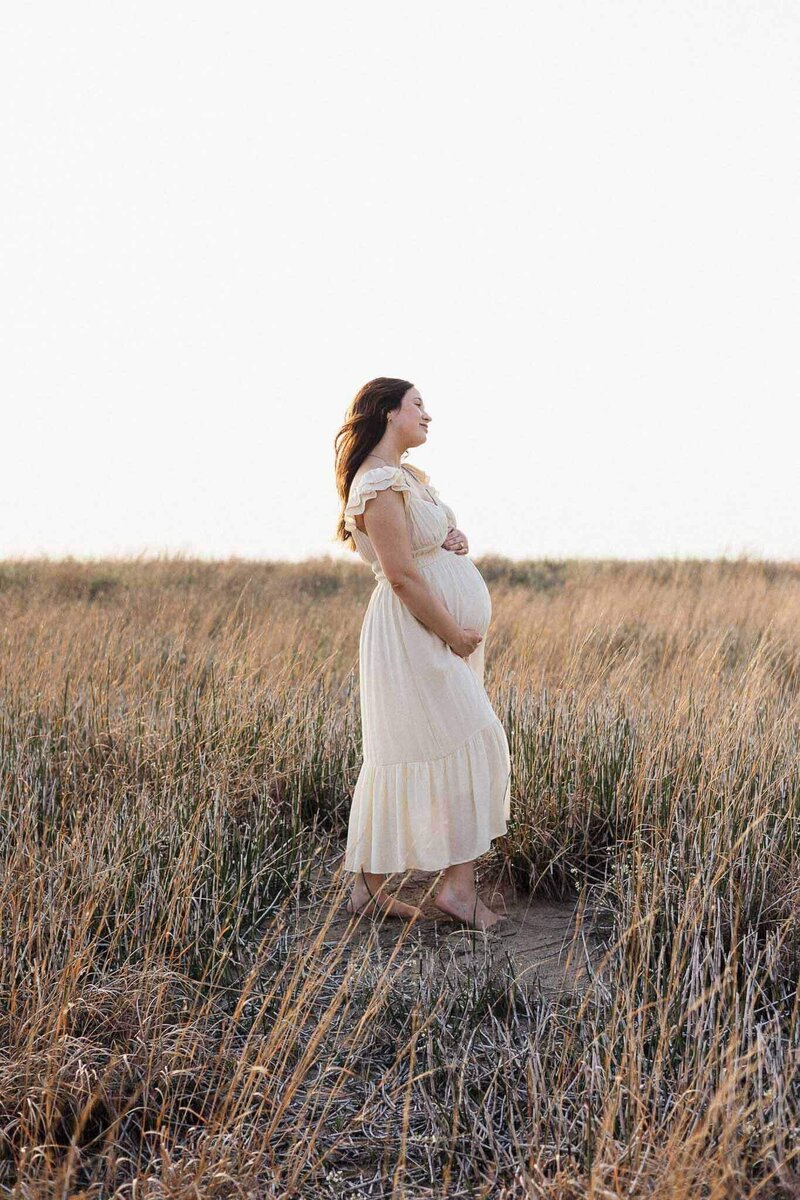 A glowing mother-to-be walks through golden Cleveland fields, embracing serenity and natural beauty during her maternity shoot.