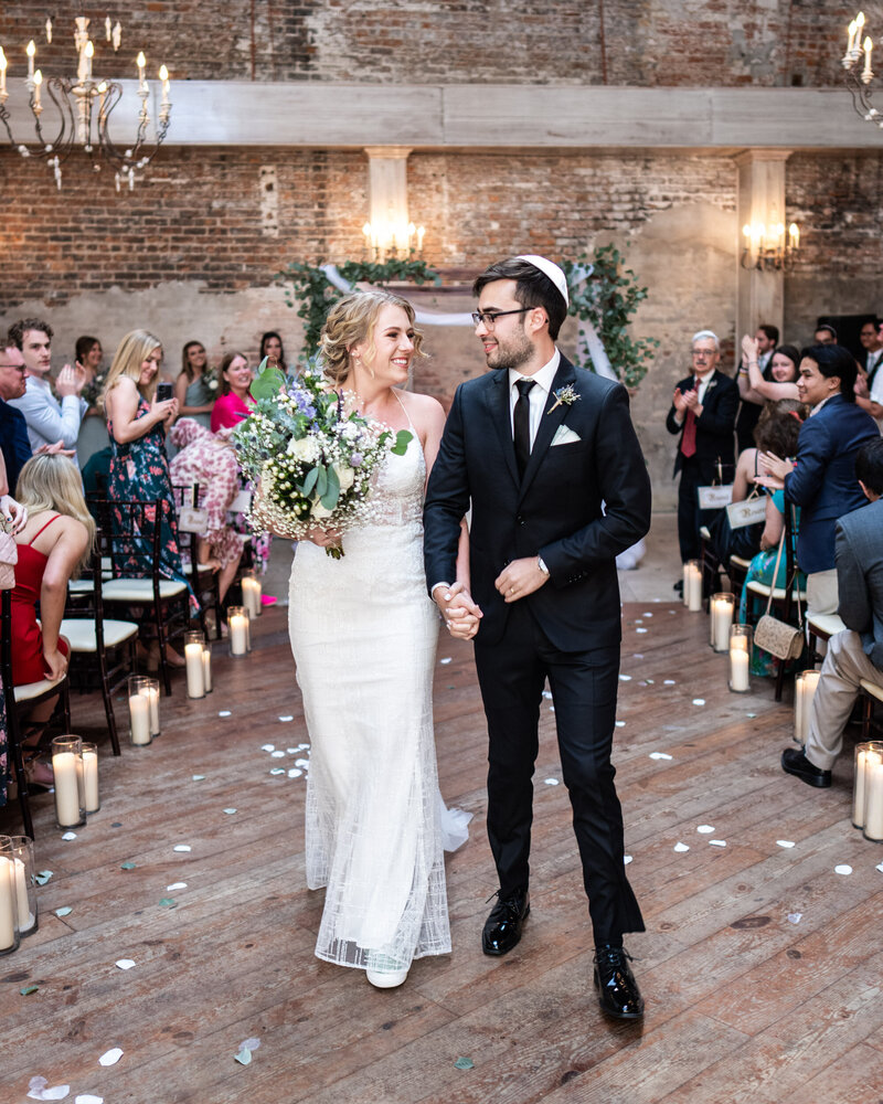 Couple walks down aisle at conclusion of wedding ceremony at Gallery Venue at Tomas Bistro