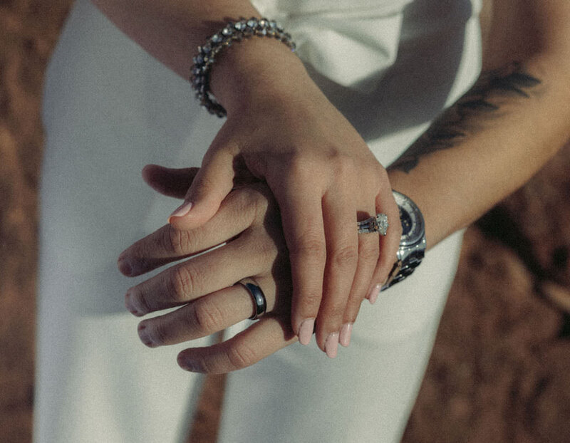 Two hands laid on top of each other showing off wedding rings.