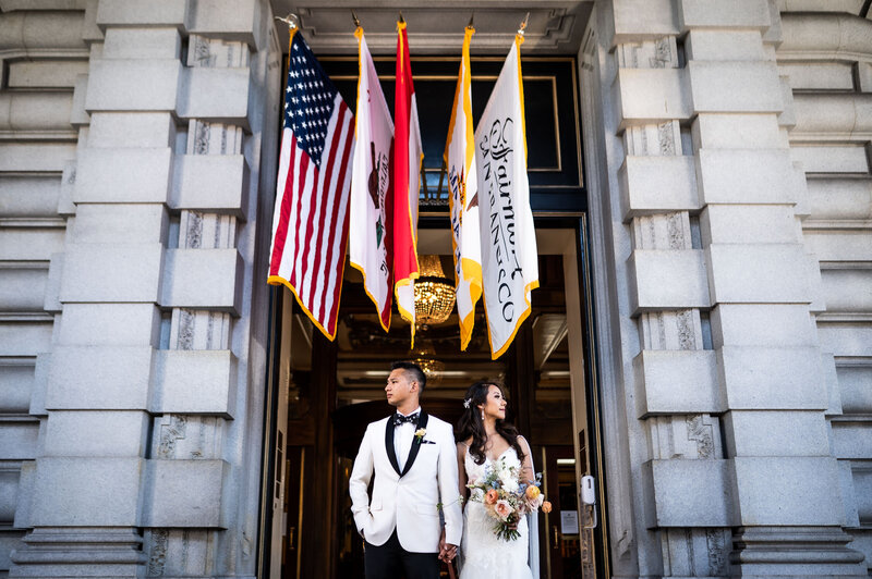 San Francisco wedding photographer creates editorial portrait of couple at Fairmont San Francisco under ceremonial flags with neoclassical architecture