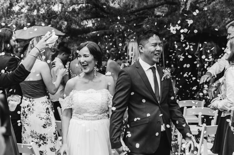black and white wedding couple walking down aisle with confetti