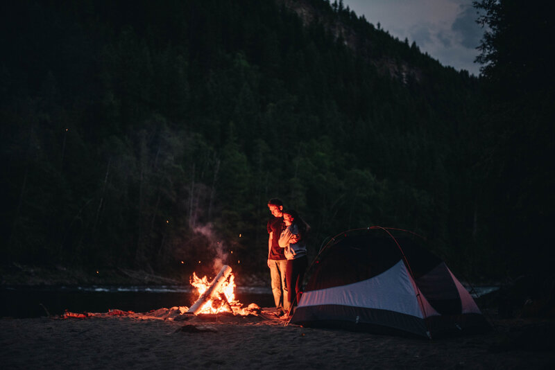 A couple camping standing by the fire