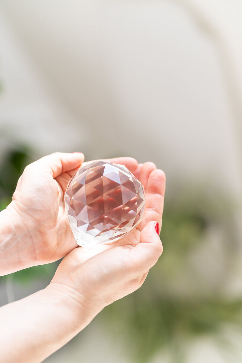 ruce držící skleněnou kouli s vybroušenými hranami