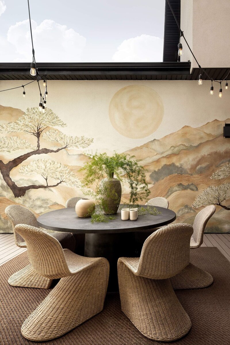 Japandi-inspired outdoor space with stone fireplace, wood decking, custom japandi mural, pendant lights, and outdoor furnishings.