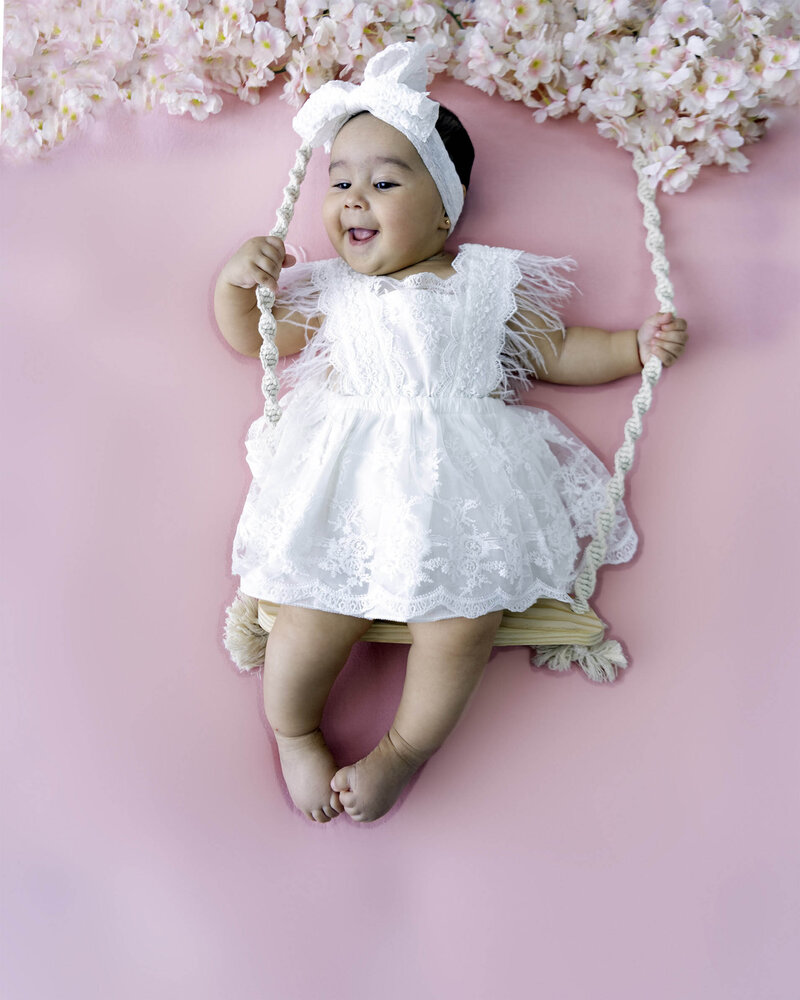 Twin baby girls sleeps in pink swaddles on a bed of pink flowers